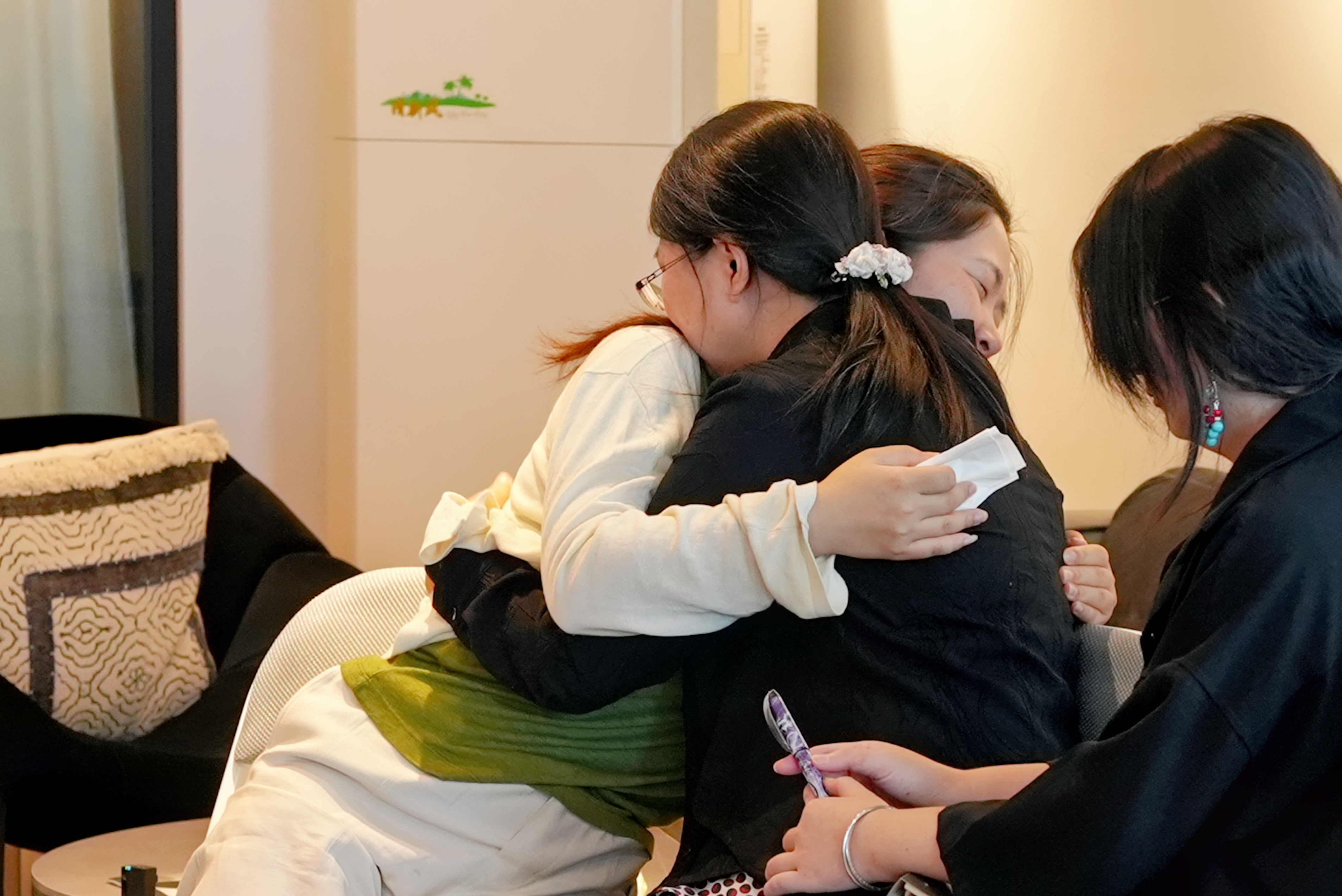 学生们围成圆圈聚集在房间里，有植物和红色地毯